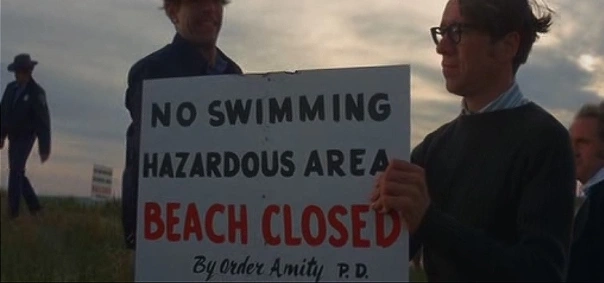 still from the movie JAWS showing a beach closed sign on Amity Island